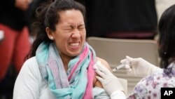 Una mujer reacciona con gesto de dolor al recibir una vacuna contra la influenza en Mesquite, Texas.