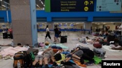 Sejumlah turis tampak menunggu jawal keberangkatan pesawat mereka di bandara setelah dievakuasi dari kebakaran yang melanda pulau Rhodes di Yunani, pada 24 Juli 2023. (Foto: reuters/Nicolas Economou)