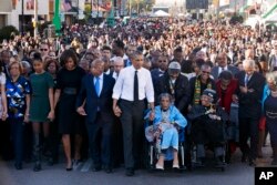 El presidente Barack Obama camina de la mano a Amelia Boynton Robinson a través del puente Edmund Pettus en Selma, Alabama, 7 de marzo de 2015, en el 50 aniversario del histórico día del movimiento de derechos civiles, que en 1965 realizó marchas de Selma a Montgomery, Alabama.