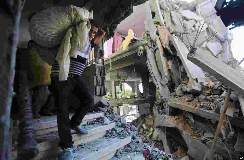 Palestinians carry belongings in a house after it was hit by an Israeli missile strike in Gaza City, July 11, 2014.