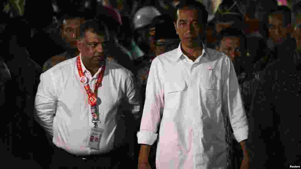 Le président Joko Widodo de l'Indonésie, à droite, marche à côté de Tony Fernandes, PDG d'AirAsie après une rencontre avec les membres de la famille des passagers à bord AirAsie vol QZ8501 à l'aéroport international de Juand, Surabaya, 30 décembre 2014.