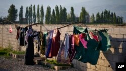 FILE - A Syrian refugee hangs her family's laundry outside her tent at a refugee camp in the town of Bar Elias, Lebanon, on July 7, 2022. Lebanon says it currently hosts around 2 million people from neighboring Syria — the world's highest number of refugees per capita.