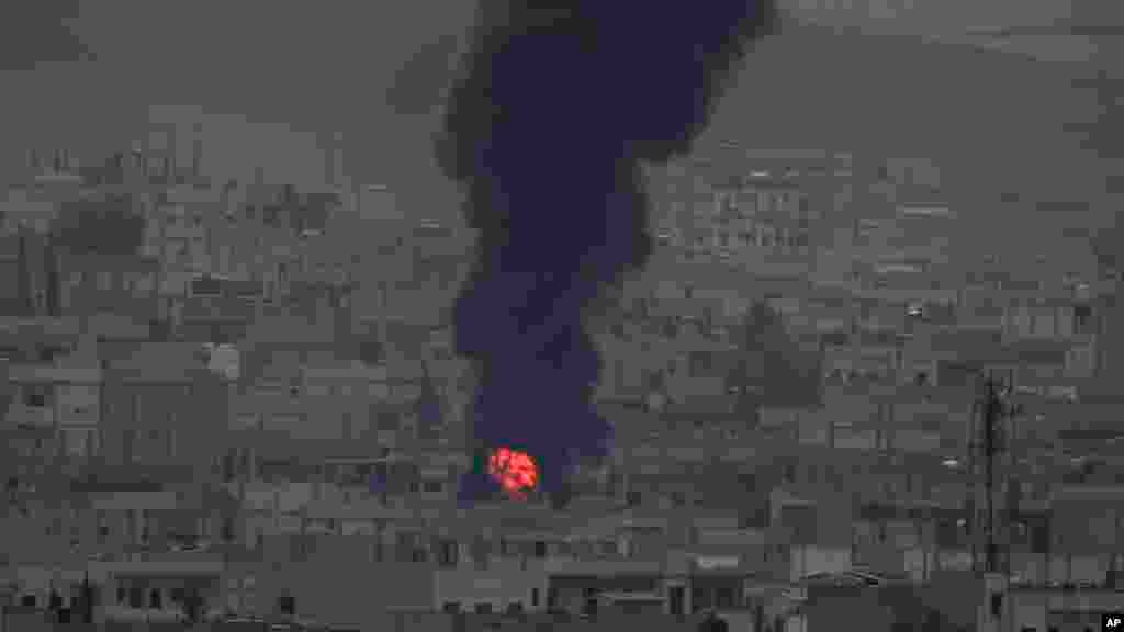 Thick smoke and flames from a fire rises following a strike in Kobani, Syria, during fighting between Syrian Kurds and the militants of the Islamic State group, as seen from a hilltop on the outskirts of Suruc, at the Turkey-Syria border, Oct. 19, 2014.