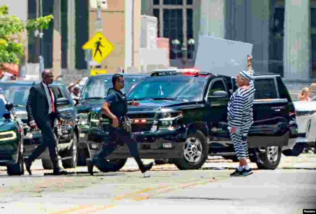 La policía y agentes de seguridad acordonaron previamente la zona por razones de seguridad. Un hombre hace un gesto cuando la caravana del expresidente de los Estados Unidos, Donald Trump, llega al Palacio de Justicia.