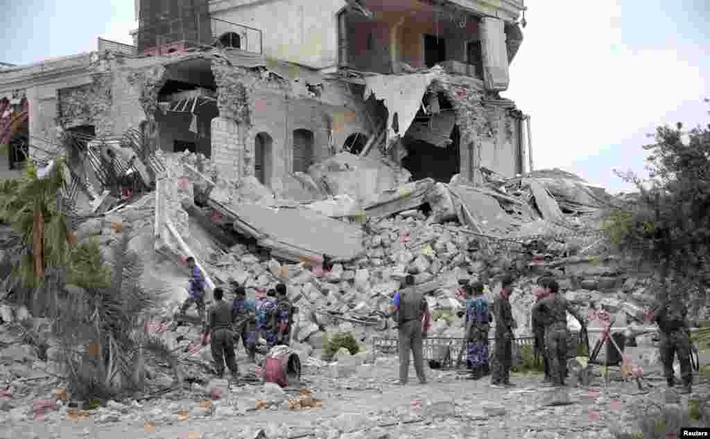Forces loyal to President Bashar al-Assad stand on debris of a hotel used by al-Assad's forces, in historic Aleppo May 8, 2014.