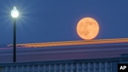 In this 2014 file photo, traffic streaks by the supermoon as it rises behind the Memorial Bridge in Washington, Saturday, July 12, 2014. (AP Photo/J. David Ake)