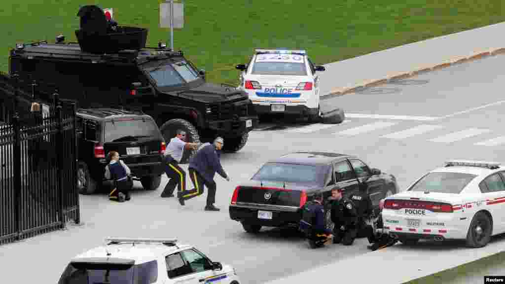 Des policiers se mettent à couvert à proximité du Parlement Hilll après une fusillade à Ottawa, Canada, le 22 octobre 2014. REUTERS/Chris Wattie