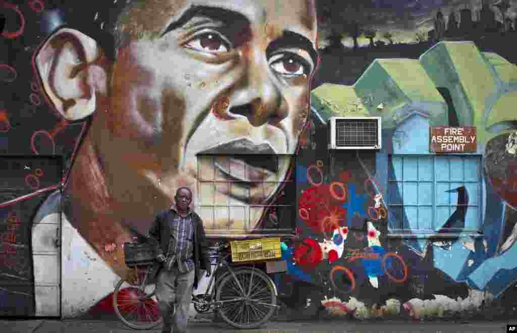 Un homme s'éloigne de sa bicyclette arrêtée contre une peinture murale du président Barack Obama, créée par l'artiste Bankslave au Centre des arts de GoDown à Nairobi , au Kenya, le 22 juillet 2015.