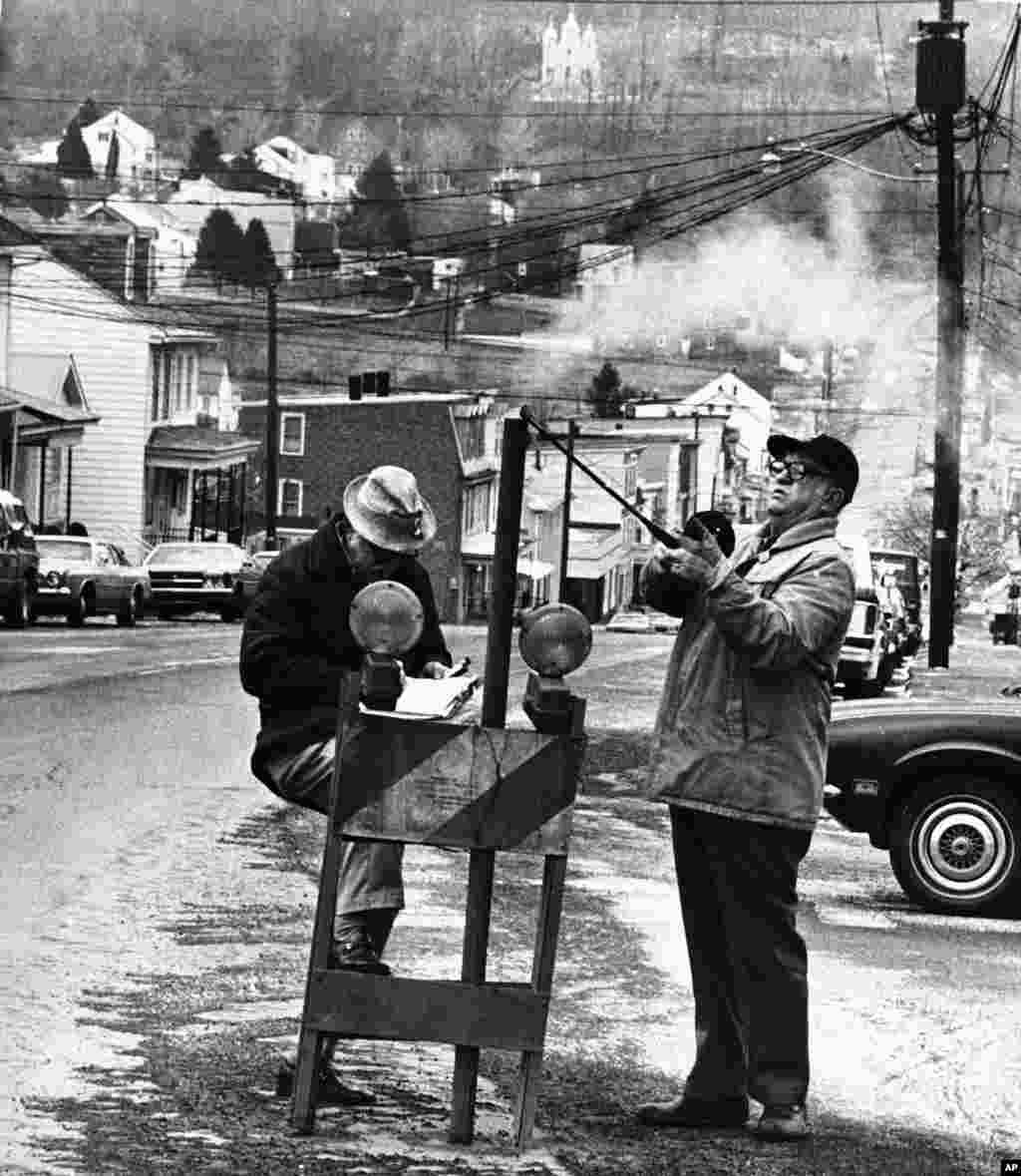 FILE - An April, 1981 photo shows U.S. Bureau of Mines' John Stockalis (R) and Dan Lewis dropping a thermometer through a hole on Main Street in Centralia, Pa., to measure heat from a shaft mine blaze that had been burning under the town since 1962. (AP)