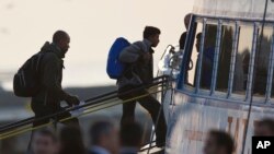 Мігранти входять на борт порому, який доставить їх до Туреччини