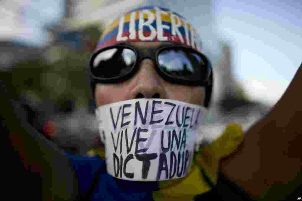 A woman wears a banner over her mouth with a message that reads in Spanish: "Venezuela lives in a dictatorship" during a protest, in Caracas, March 31, 2017.