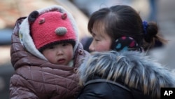 FILE - A Chinese woman cuddles her child in Beijing, China. China announced it was ending its long-standing one-child policy and will now allow all couples to have two children.