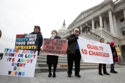 Manifestantes protestan frente al Capitolio de Estados Unidos, el viernes 31 de enero de 2020, en Washington mientras los senadores continuaban el juicio político contra el presidente Donald Trump.