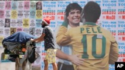 Un hombre empuja un carrito lleno de basura para reciclar frente a un mural en el que se muestra al astro brasileño Pelé abrazando a la difunta estrella del fútbol, el argentino Diego Maradona, en Sao Paulo, Brasil, el 24 de diciembre de 2022. 