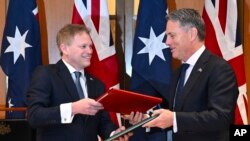 2024年3月21日，英国国防大臣格兰特·沙普斯（Grant Shapps，左）和澳大利亚国防部长理查德·马勒斯（Richard Marles）在澳大利亚议会交换新签署的国防和安全合作协议。