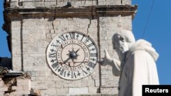A statue of St. Benedict gestures toward the damaged town hall clock tower in the ancient town of Norcia, Italy, Oct. 31, 2016.