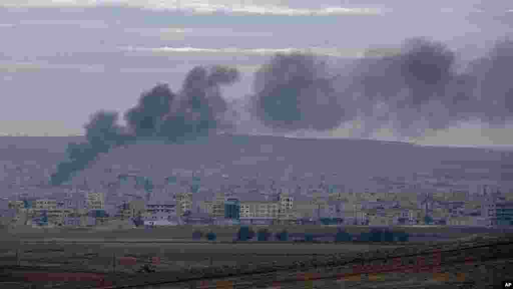 Smoke from a fire rises following a strike in Kobani, Syria, during fighting between Syrian Kurds and the militants of Islamic State group, as seen from a hilltop on the outskirts of Suruc, at the Turkey-Syria border, Oct. 19, 2014.