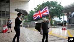 Seorang aktivis prodemokrasi Alexandra Wong memegang bendera Inggris Raya dalam persidangan beberapa aktivis di Hong Kong yang dituntut dengan tuduhan subversi pada 23 September 2021. (Foto: AP/Kin Cheung)