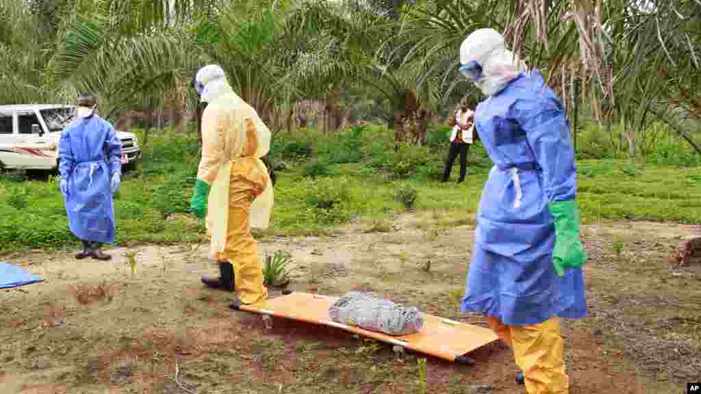Des agents de la santé, vêtus d’équipement de protection contre le virus Ebola, transportent sur une civière la dépouille d'un enfant nouveau-né suspecté mort après avoir contracté l’épidémie.