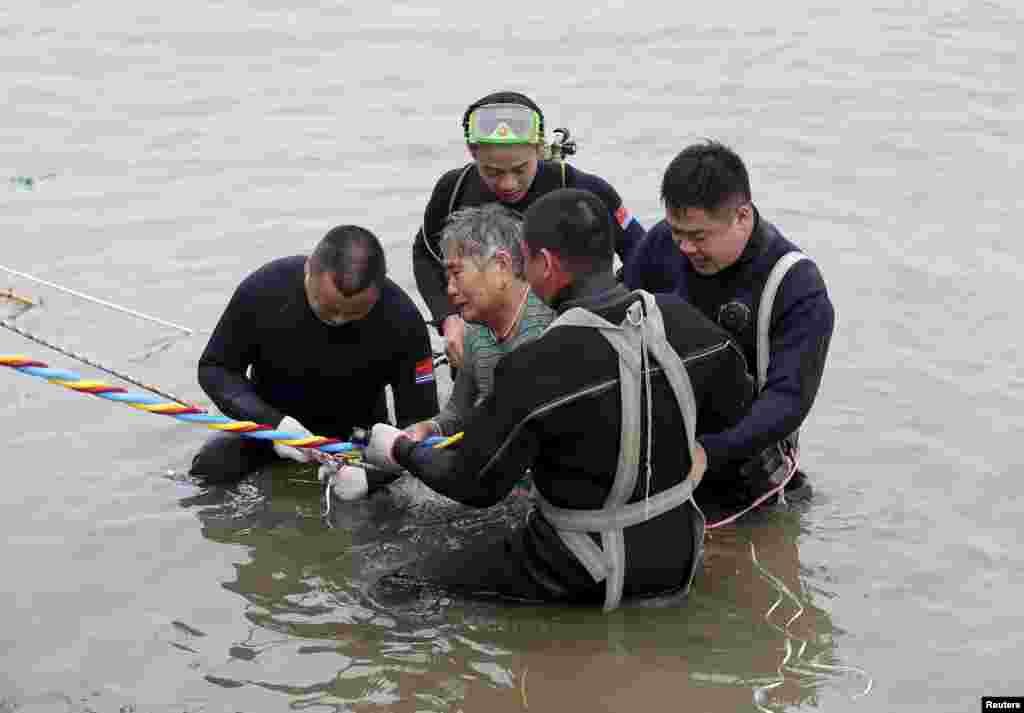 A woman is helped by divers from a sunken ship in Jianli, Hubei province, China, June 2, 2015. Divers pulled the 65-year-old woman from the hull of the passenger ship carrying 458 people that capsized on China's Yangtze River and others could still be alive, state media said on Tuesday.