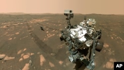FILE - The Perseverance Mars rover, foreground, is pictured with the Ingenuity helicopter about 13 feet (3.9 meters) behind it, April 6, 2021.