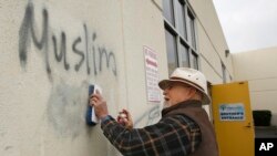 Tom Garing, un jubilado voluntario limpia un grafitti pintado en la pared de una mezquita en Roseville, California.
