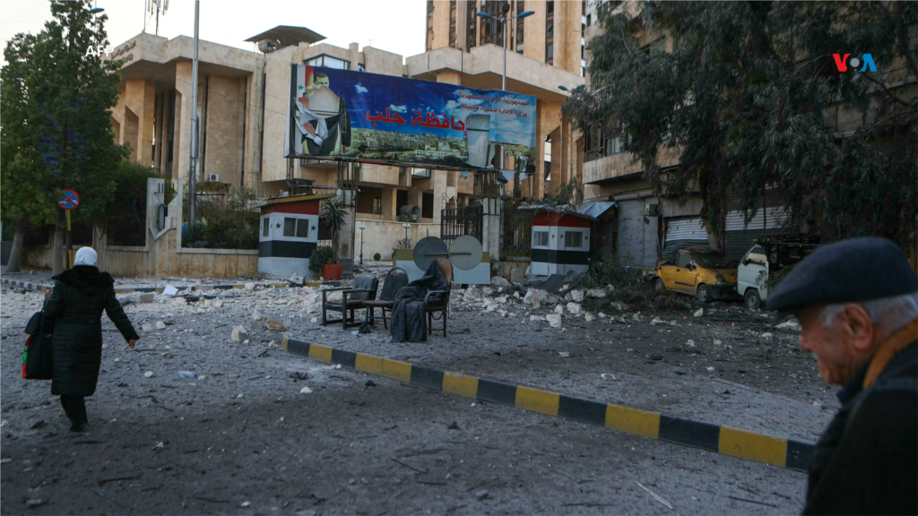 Personas caminan cerca a los escombros de un edificio dañado por los ataques aéreos del régimen sirio en la provincia de Idlib, al noroeste de Siria.