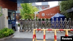 A staff member stands at an entrance to a closed school amid the COVID-19 outbreak in Beijing, China, April 28, 2022.