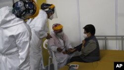 Un médico revisa los signos vitales de una anciana luego de ser inoculada con una dosis de la vacuna Pfizer COVID-19 como parte del período de observación, en el centro de convenciones convertido en sitio de vacunación, en Quito, Ecuador, el 31 de marzo. 