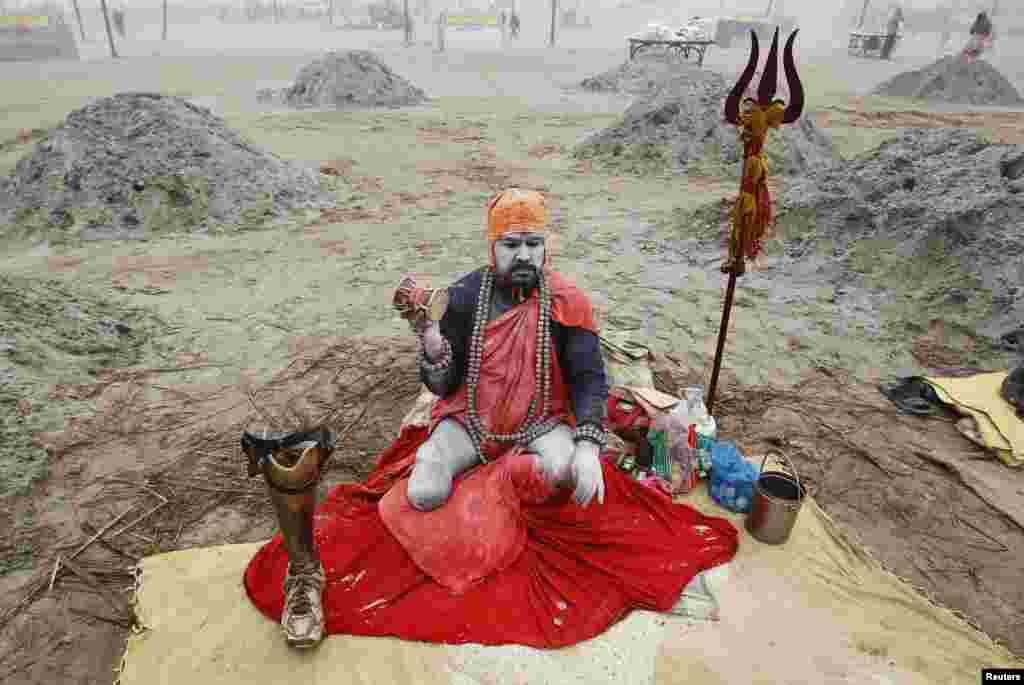 Seorang Sadhu, atau orang suci agama Hindu di India, duduk di pinggir sungai Gangga dengan kaki palsunya di kota Allahabad, India utara.