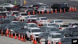 Lines of cars wait at a drive-through coronavirus testing site, July 5, 2020, outside Hard Rock Stadium in Miami Gardens, Fla. Florida that has reached a grim milestone:more than 200,000 people tested positive for the novel coronavirus.