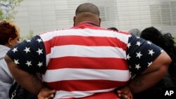 FILE - In this May 8, 2014 photo, an overweight man wears a shirt patterned after the American flag during a visit to the World Trade Center, in New York. 