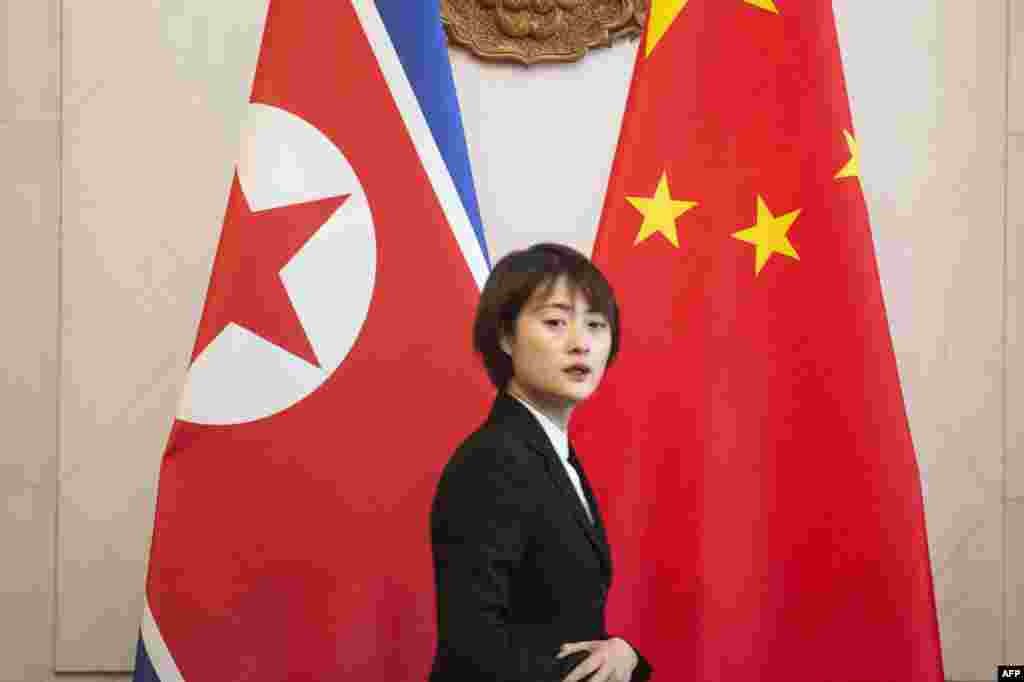 2018年12月7日,在朝鲜外相李勇浩与中国外交部长王毅在北京钓鱼台国宾馆会晤前,一名服务员走过朝鲜和中国国旗。
