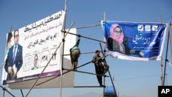 Des hommes installent des affiches électorales à Kaboul, en Afghanistan, le 9 octobre 2018.