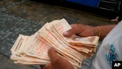 En esta imagen de archivo, tomada el 5 de agosto de 2021, un hombre cuenta billetes por el equivalente a un dólar en una parada de autobús en Caracas, Venezuela. Foto AP.