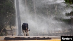 Un periodista es alcanzado por el chorro de un cañón de agua mientras cubre una protesta contra el alza de los precios de la energía en Tegucigalpa, Honduras, el 2 de junio de 2018.
