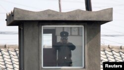 지난 4월 북한 접경도시 신의주의 국경 초소에서 북한 병사가 망원경으로 중국 쪽을 바라보고 있다. 압록강 너머 중국 단둥에서 촬영한 사진이다. (자료사진)