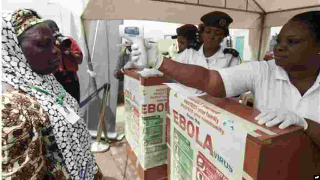 Wani jami’in kula da lafiyar matafiya na amfani da ma’aunin zafin jiki ya na yiwa Maniyyata gwajin cutar Ebola a ranar goma sha takwas ga watan satumba shekarar dubu biyu da goma sha hudu, 18 ga Satumba, 2014..