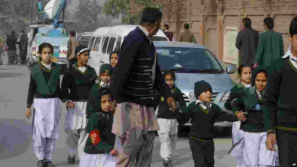 Un agent de sécurité en civil escorte élèves sauvés de l'école à proximité lors d'une attaque des talibans à Peshawar, au Pakistan, le mardi 16 décembre 2014.