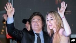 El presidente electo de Argentina, Javier Milei, y su pareja Fátima Flores, saludan a sus partidarios en su sede de campaña después de ganar el balotaje, el 19 de noviembre de 2023.