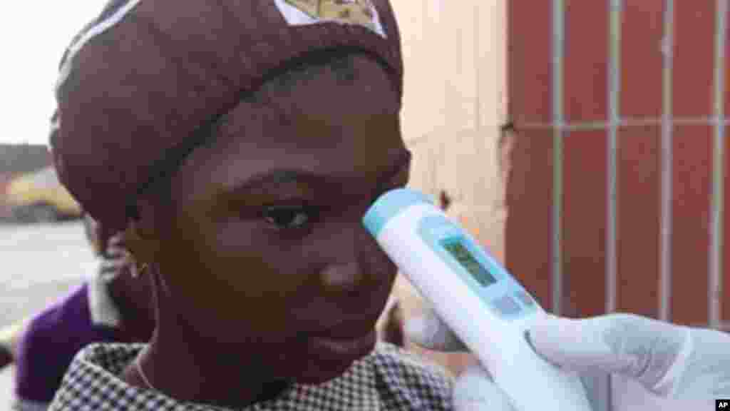 Wani Malami na amfani da na’urar auna zafin jiki domin neman alamun cutar Ebola.