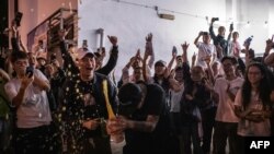 Seorang pendukung pro-demokrasi membuka botol sampanye di luar tempat pemungutan suara untuk merayakan kekalahan kelompok pro-Beijing dalam pemilu dewan lokal di Hong Kong, 25 November 2019. 