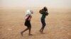 Women wrapped in shawls walk through a sandstorm in Timbuktu, July 29, 2013.