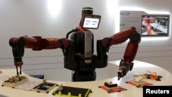 FILE - A Baxter robot of Rethink Robotics picks up a business card as it performs during a display at the World Economic Forum (WEF), in China's port city Dalian, Liaoning province, China onSept. 9, 2015. 