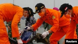 Indonesian rescue members inspect what is believed to be the remains of the Sriwijaya Air plane flight SJ182, which crashed into the sea, at Jakarta International Container Terminal port in Jakarta, Indonesia, Jan. 10, 2021.