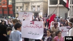 Niños y mujeres sirios pueden ser vistos en la foto tomada por ciudadanos con teléfonos celulares, con carteles donde reclaman la salida de al-Assad del poder.