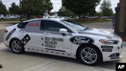 FILE - An Aug. 24, 2017, photo, shows the specially designed delivery car that Ford Motor Co. and Domino’s Pizza will use to test self-driving pizza deliveries, at Domino’s headquarters in Ann Arbor, Michigan.