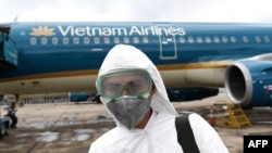 FILE - A worker wearing a protective suit prepares to disinfect a Vietnam Airlines plane amid concerns of the spread of the COVID-19 coronavirus, March 3, 2020, at Noi Bai International Airport in Hanoi.
