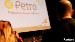 FILE - The new Venezuelan cryptocurrency the Petro logo is seen as Minister for University Education, Science and Technology Hugbel Roa talks to the media during a news conference in Caracas, Venezuela, Jan. 31, 2018.