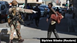Un membre des Forces de défense nationale sud-africaines demande à un sans-abri de déguerpir, à Johannesburg, Afrique du Sud, le 27 mars 2020. (Photo: REUTERS/Siphiwe Sibeko)